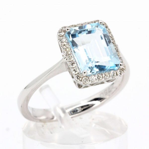 Emerald Cut Blue Topaz Ring with Halo of Diamonds Set in 18ct White Gold